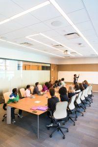Large desk, conference style, with several people sitting around it.